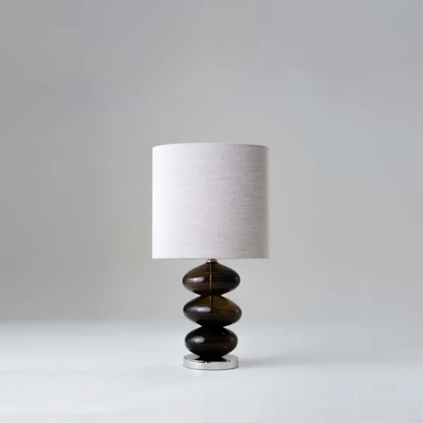 Glass table lamp with a stacked smoked-amber borosilicate glass body and natural linen shade