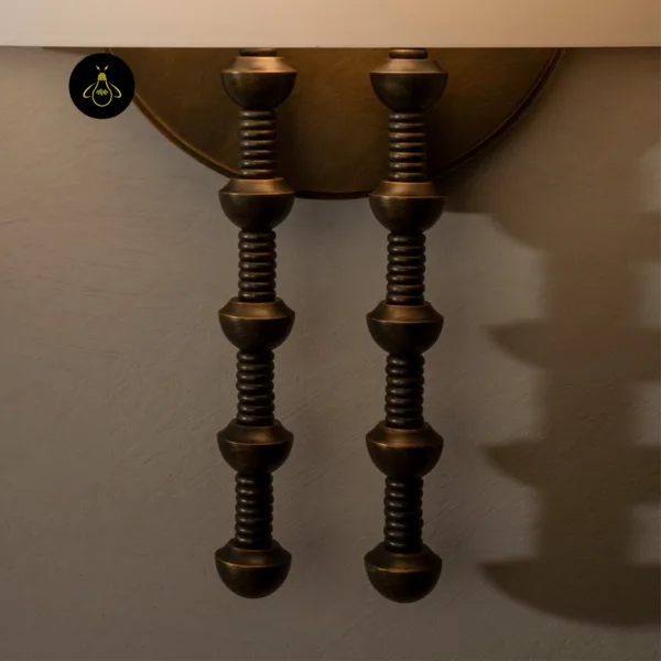 Close-up of the alabaster dome wall light twin turned rods in antique brass finish on 304 stainless steel