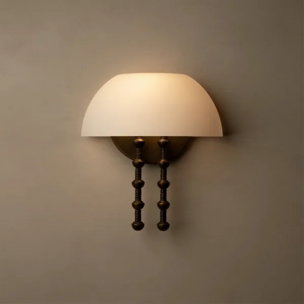 Alabaster dome wall light lit warm on a grey plaster wall, half-dome stone shade over twin turned rods
