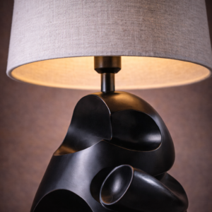 Asymmetrical table lamp lit close-up with warm under-shade glow