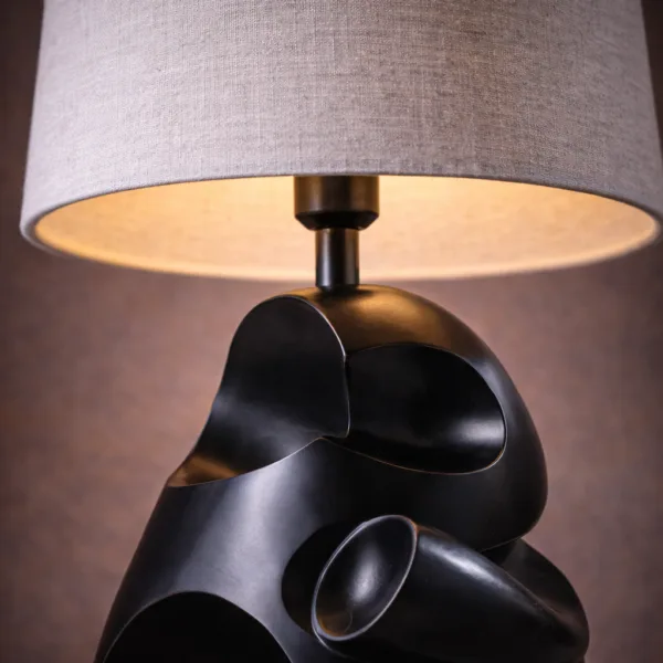 Modern table lamp lit detail with warm glow through the linen shade