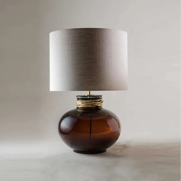 Amber borosilicate glass lamp with a glossy toffee vessel base, gold collar and linen drum shade