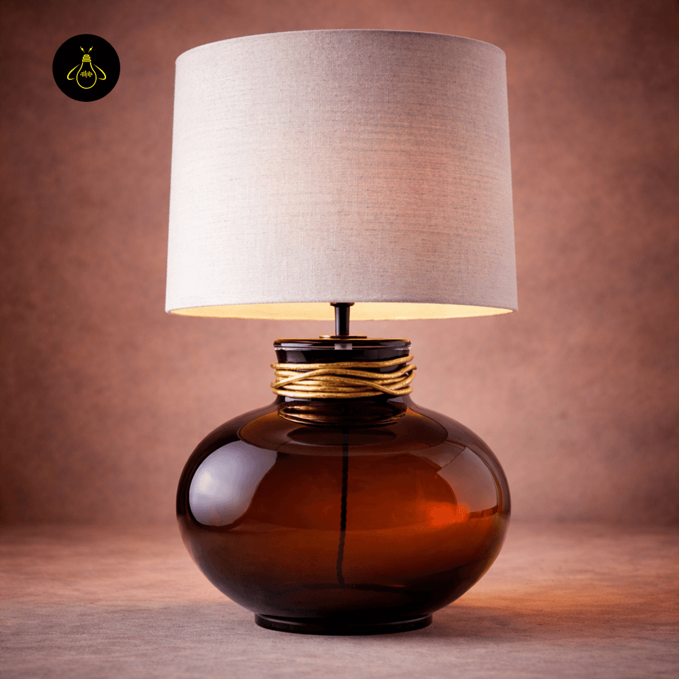 Amber Glass Lamp – Boudica Modern Bedside Table Lamp, 62 cm 2 Amber glass lamp lit, glowing warmly through its linen drum shade