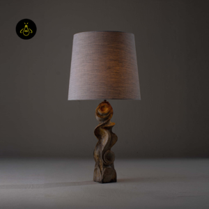 Dorian table lamp shown lit with sculptural burnt wood base