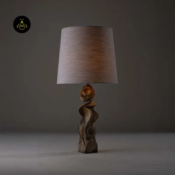 Sculptural table lamp lit, showing carved burnt-wood base detail