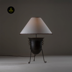 Living room table lamp lit to show dark sculptural base and stitched fabric shade