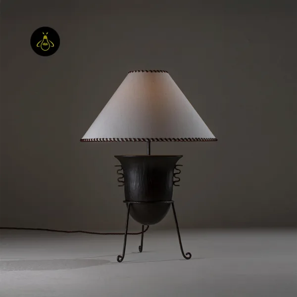 Wood table lamp lit to show its warm ambient glow through the whip-stitched fabric shade