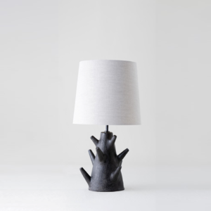 Rustic table lamp with dark wood branch base and fabric shade on a light background