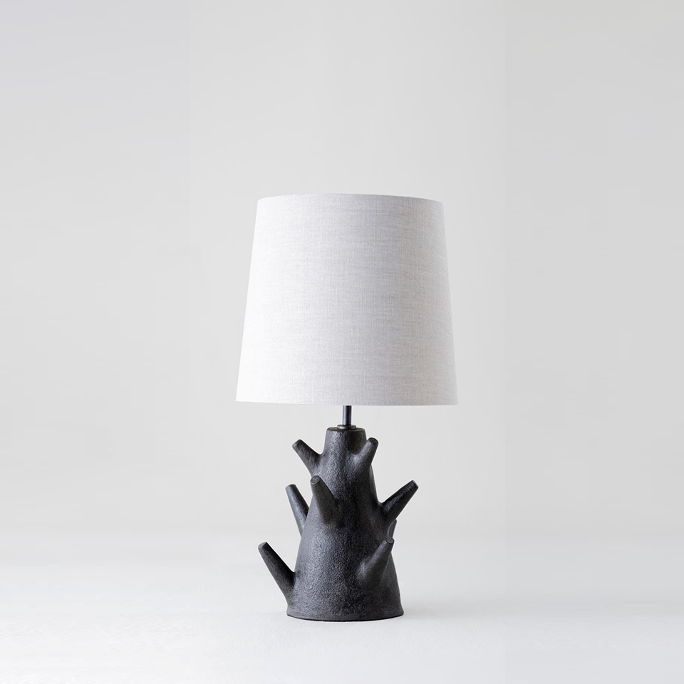 Rustic table lamp with dark wood branch base and fabric shade on a light background