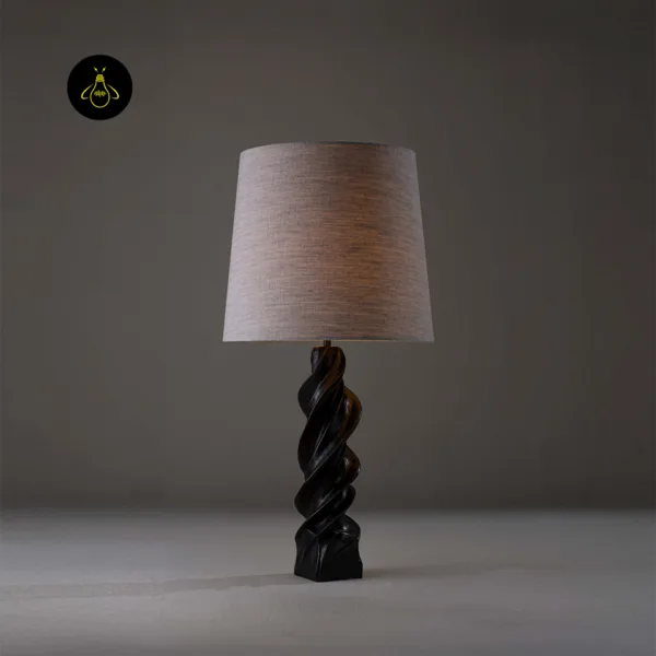 Spiral wood table lamp lit with warm ambient glow and barley-twist base