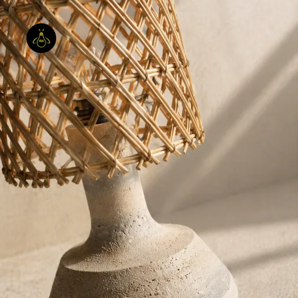Close-up of the rattan table lamp showing the open woven cane lattice and travertine texture