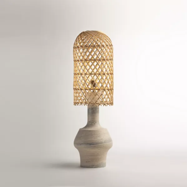 Rattan table lamp with a tall woven dome shade on a sculptural travertine base