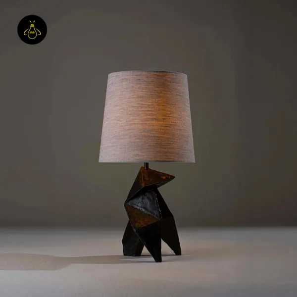 Geometric origami table lamp lit with warm ambient glow through linen shade