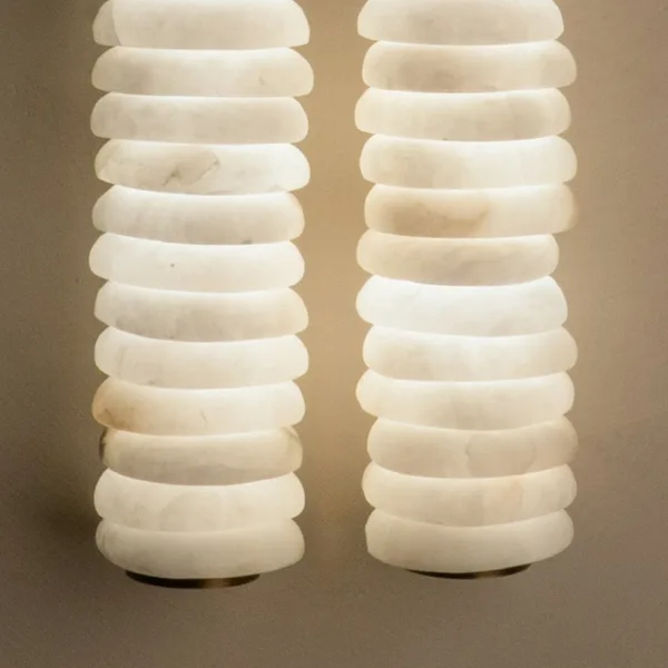 Close-up of the stacked alabaster wall light glowing, showing the natural veins in each hand-carved white alabaster disc