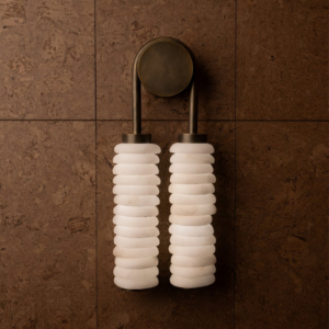 Designer wall light styled on a neutral wall to show the soft glow through the alabaster drops