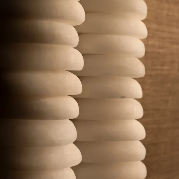 Side close-up of the rounded, hand-carved alabaster discs stacked in the two columns of the stacked alabaster wall light