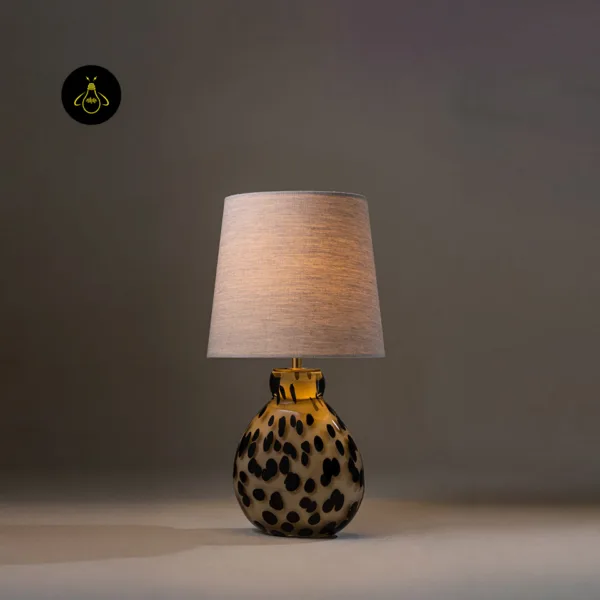 Glass table lamp with spotted handblown body and tapered linen shade for a bedroom side table