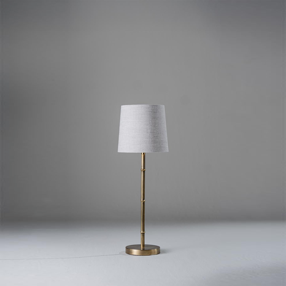 Mini table lamp with slender bamboo-inspired metal stem and fabric shade on a neutral background
