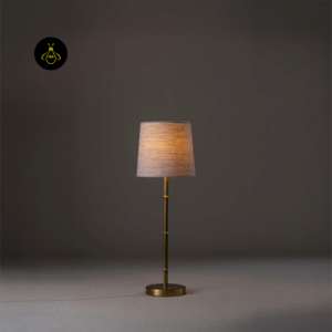 Mini table lamp lit to show warm glow through the fabric shade