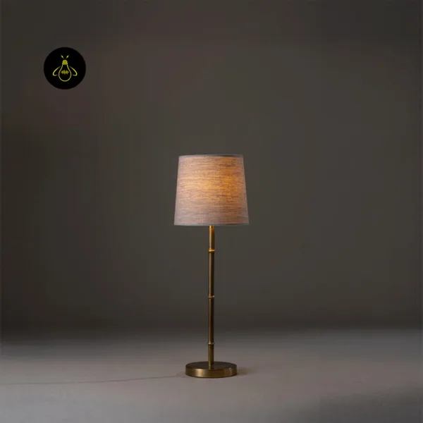 Mini brass table lamp in a studio shot with the linen shade softly illuminated