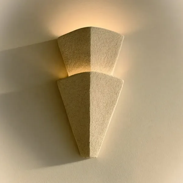 Decorative wall light in textured ivory stainless steel, two tapered tiers lit warm on a cream wall