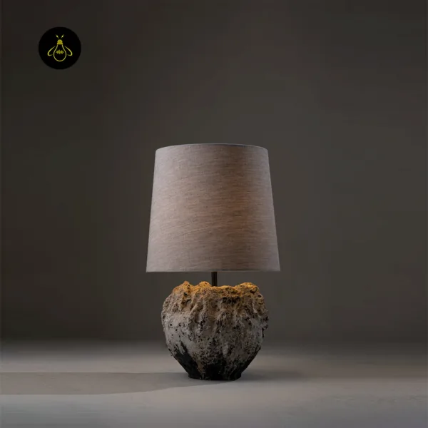 Wabi sabi table lamp lit, casting a warm diffused glow through its linen shade