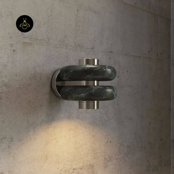Green marble wall light on a concrete wall, dark veined stone bands and silver stainless steel parts, warm light below