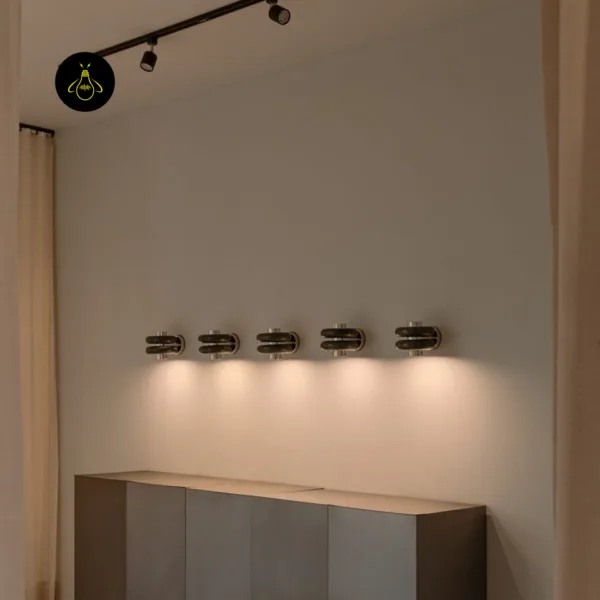 Five green marble wall lights in a row above a sideboard, each lighting the wall below