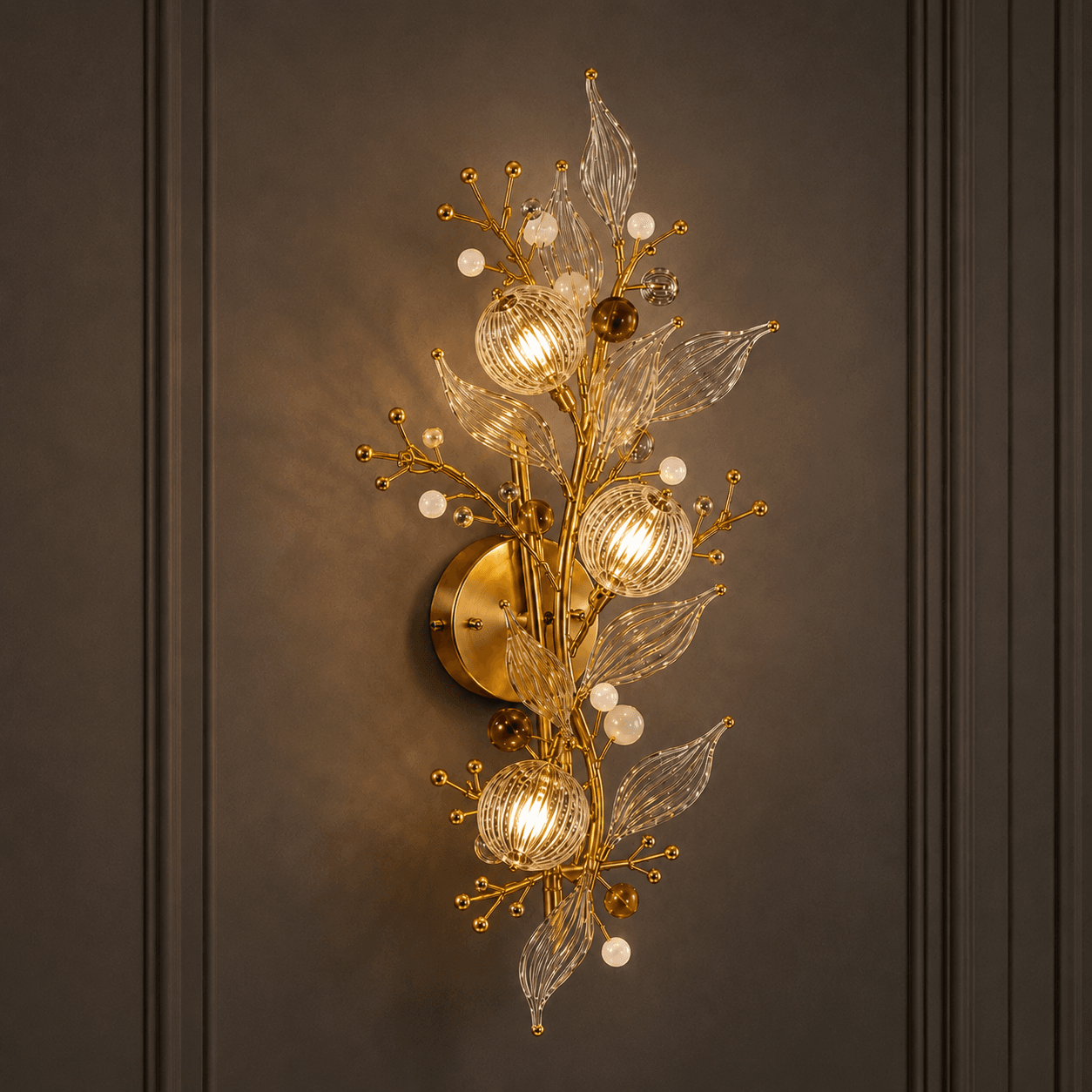 Crystal botanical wall sconce on dark paneled wall — gold branch bouquet with three ribbed glass globe shades, amber orbs and opal beads, warm filament glow — JagMag Lights JML-416