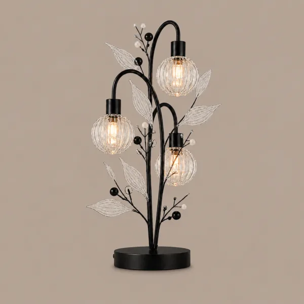 Crystal berry botanical table lamp on warm beige background lit — three ribbed glass globe cage shades on arching black branches with clear borosilicate glass leaves and pearl berry bead accents