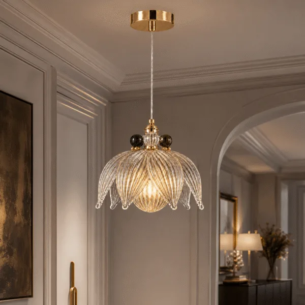 Glass flower pendant light hanging in a panelled corridor, lit, clear ribbed borosilicate glass petals with dark glass orbs at the collar and a polished gold canopy