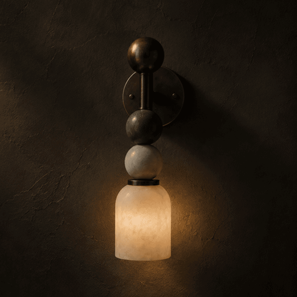 Alabaster vanity light lit against a dark plaster wall, dome glowing warm