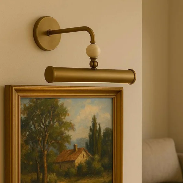 Picture wall light mounted above a framed landscape oil painting in a gilt frame, with a sofa beside it