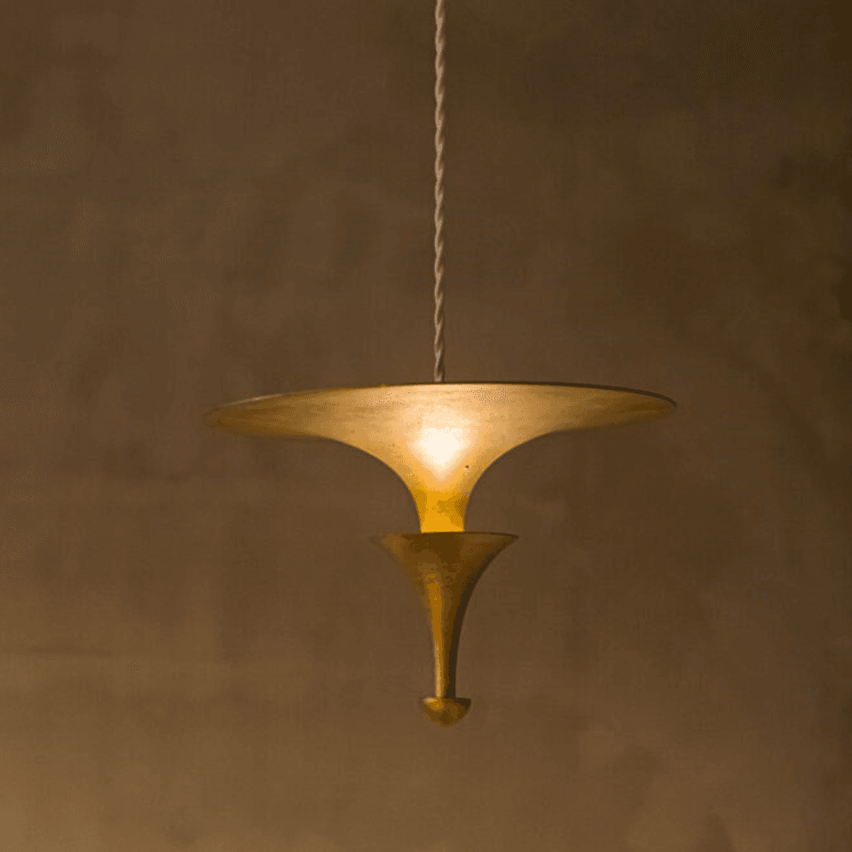 Brass uplight pendant light lit, light reflecting off the underside of the brass disc