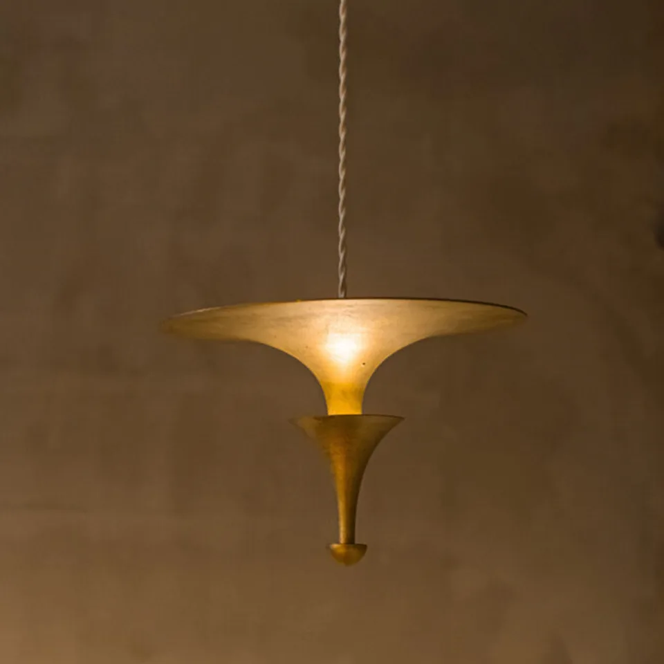 Brass uplight pendant light lit, light reflecting off the underside of the brass disc