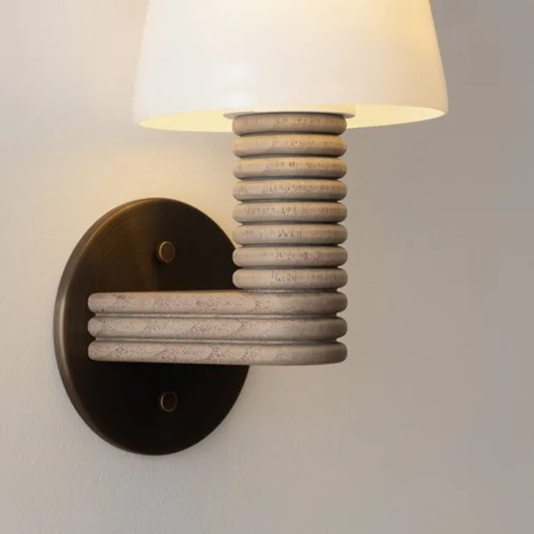 Close-up of the wooden wall sconce arm, stacked hand-turned wood rings bending into the wall plate