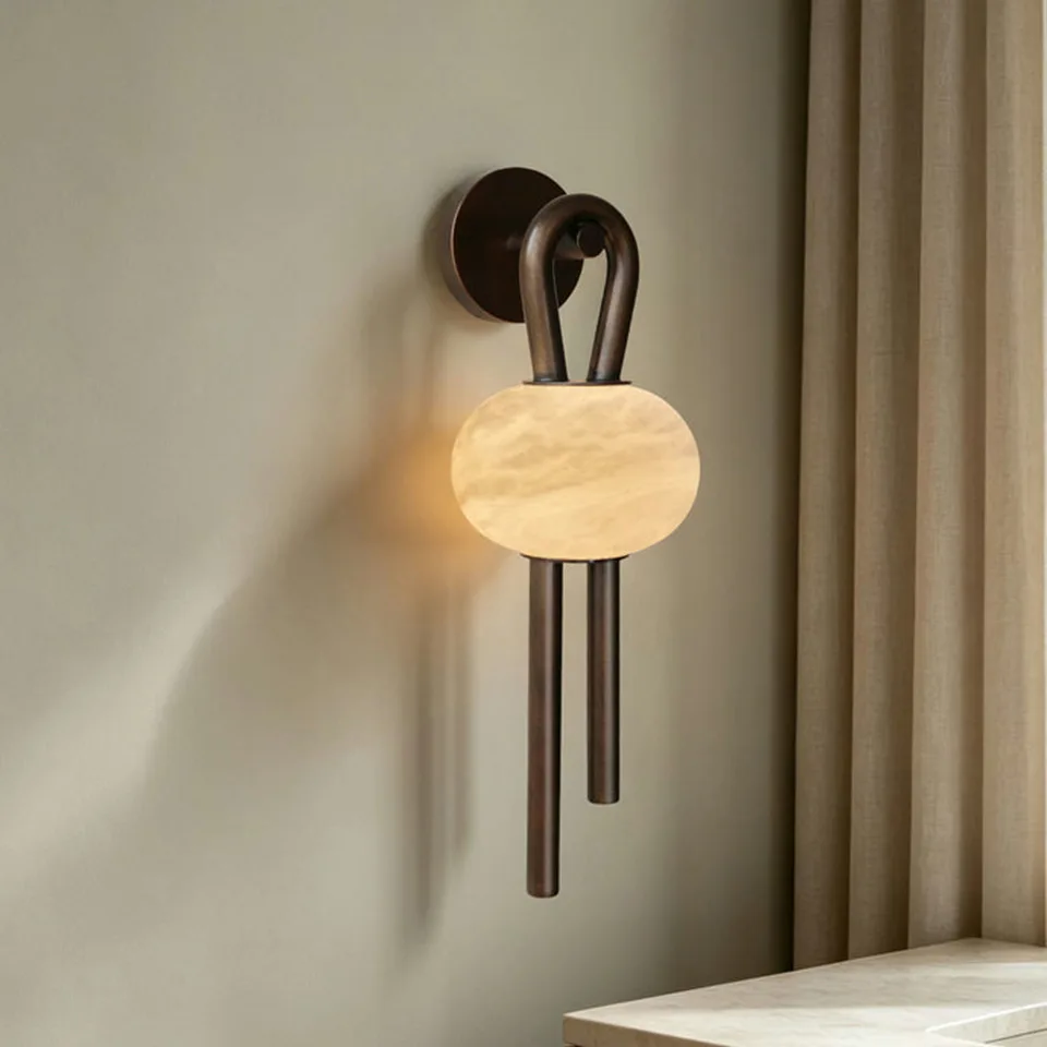 Oval Alabaster Wall Light – 53 cm Natural Stone & Bronze | Jagmag Lights 9 Oval alabaster wall light lit beside a linen curtain, showing the warm glow on the wall