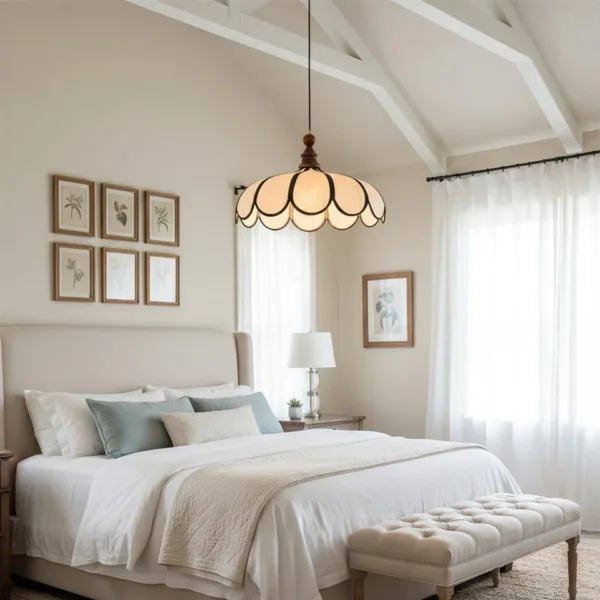 Scalloped fabric pendant light lit above a bed in a cream bedroom with a vaulted ceiling