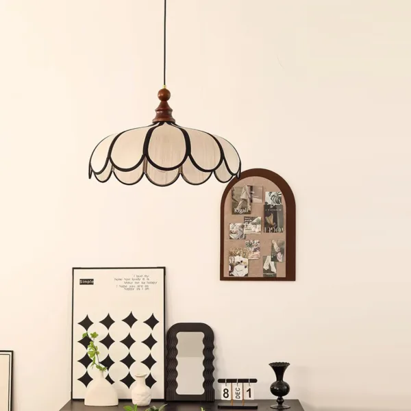 Scalloped fabric pendant light hanging above a desk with framed prints in a study