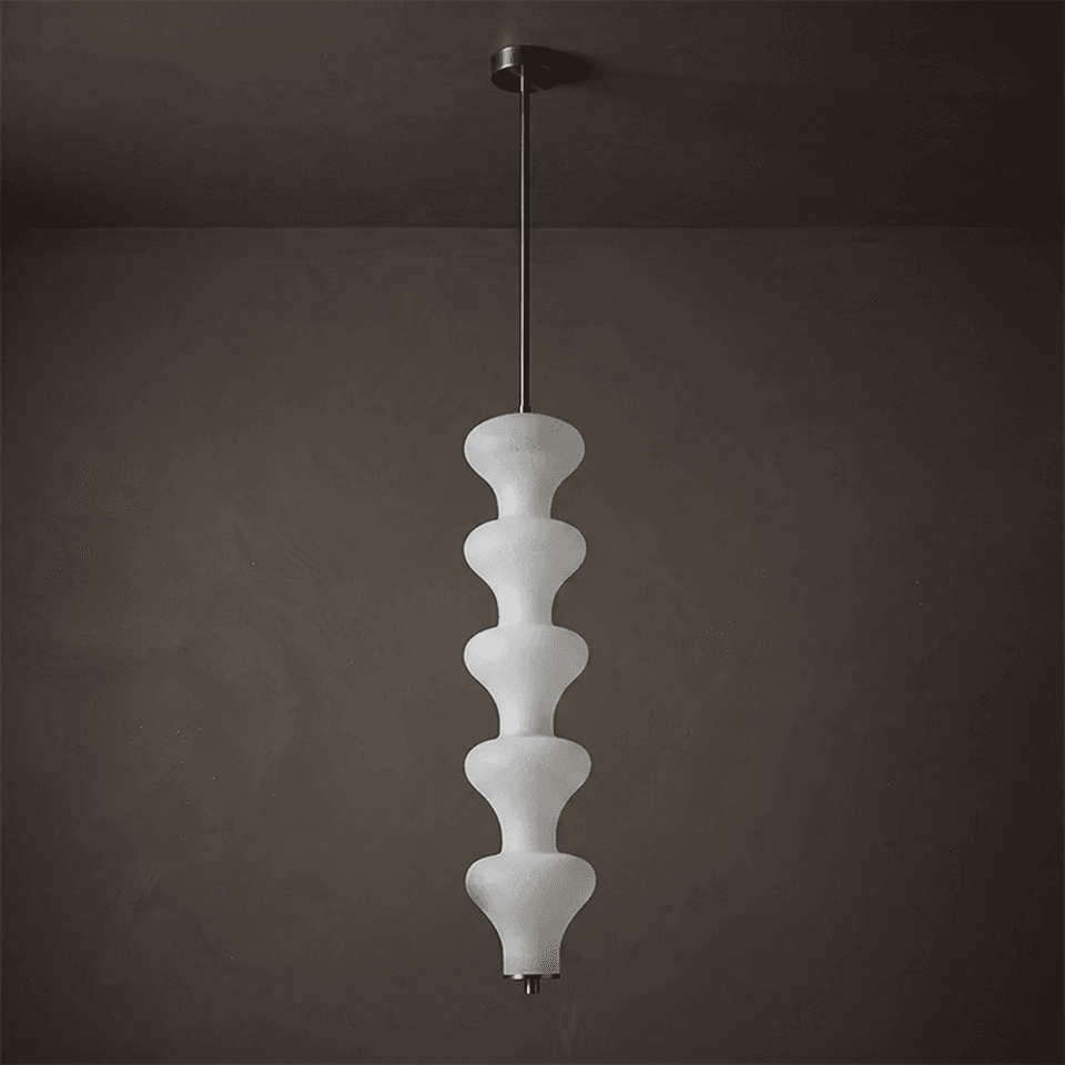 Sculptural alabaster pendant light glowing warm against a dark plaster wall