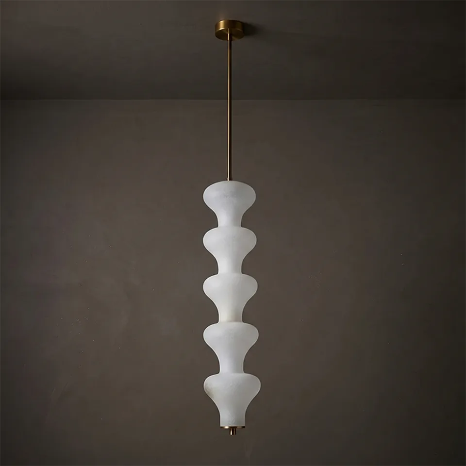 Sculptural alabaster pendant light glowing warm against a dark plaster wall