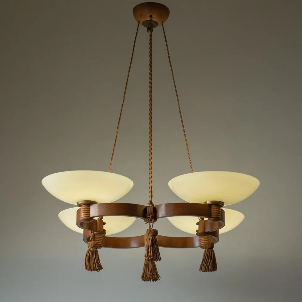 Wood and glass chandelier lit, four opal glass bowls glowing on a double wooden ring