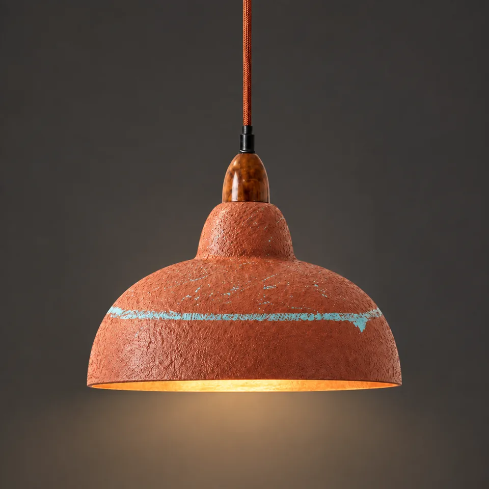 Hand-painted terracotta resin dome pendant light lit warm, showing the distressed blue-green accent line, on a dark background