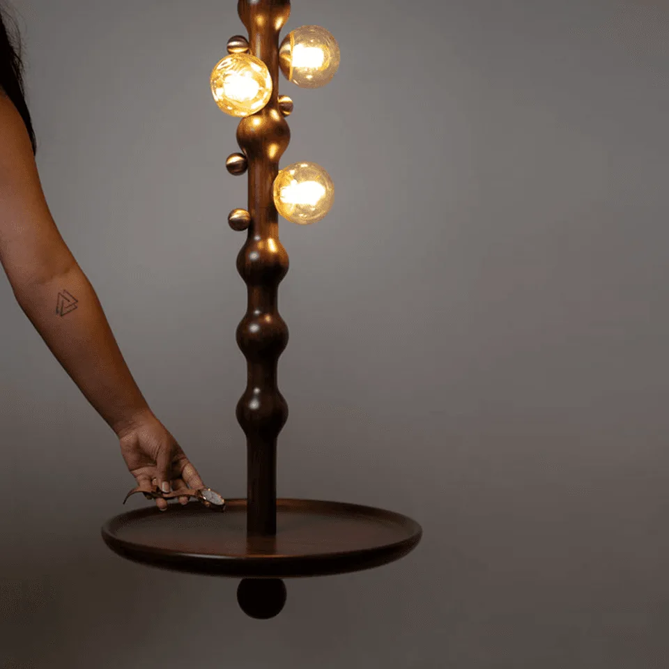 Stem Pendant Light – Sculpted Reclaimed Teak with Amber Glass Globes & Side Table | Jagmag Lights 4 Hand placing a small object on the suspended teak plate of the Stem pendant light, showing its side-table function
