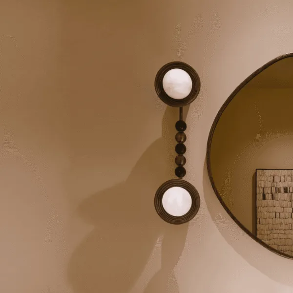 Double wall light beside a round organic mirror, both opal borosilicate glass balls lit, showing the green stone and gold steel bead stem