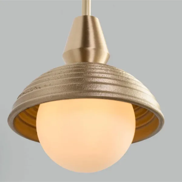 Close-up of the wood pendant light: ridged matt gold wood dome, brass-finish cap and lit opal borosilicate glass ball