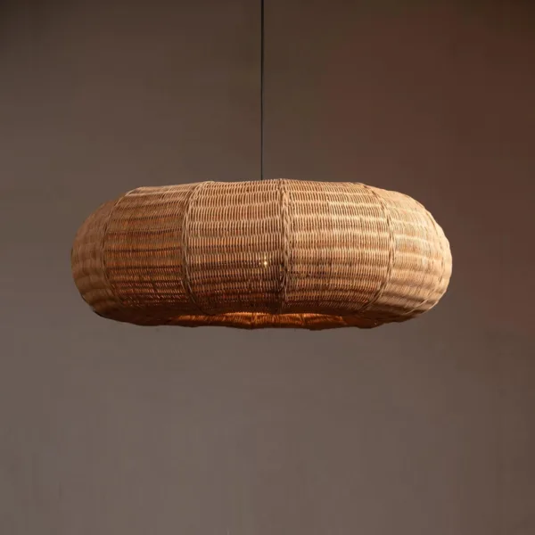 Rattan hanging light: a cane frame pendant light with a handwoven natural rattan donut shade on a dark wire against a plain wall