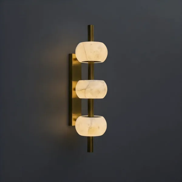 Alabaster bead wall light with three glowing stones on a brass-finish rod, grey wall