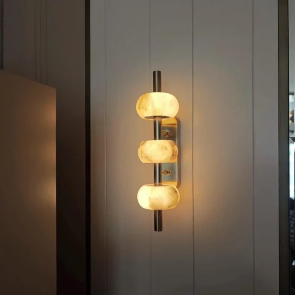 Alabaster bead wall light glowing on a white panelled wall