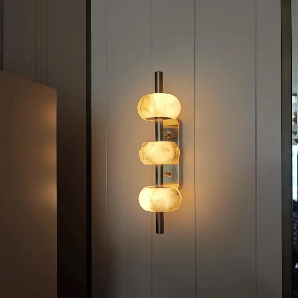 Luxury Wall Light – Three Alabaster Beads, Brass Finish, 38 cm 3 Alabaster bead wall light glowing on a white panelled wall
